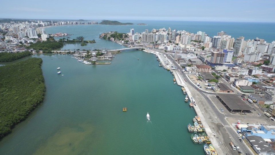 Vista aérea do canal de Guarapari com barcos atracados, a mata e a cidade